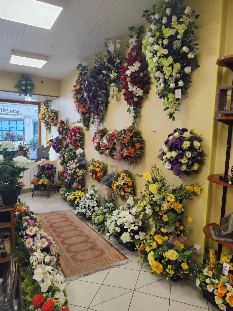 Exposition de couronnes de fleurs funéraires sur les murs de la boutique